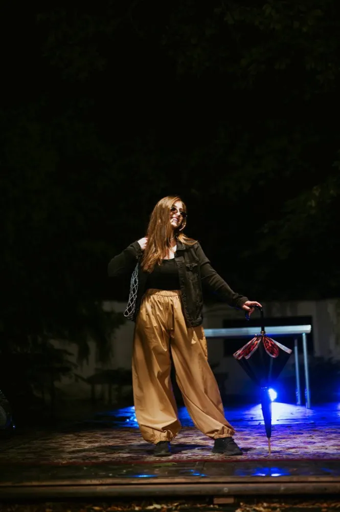 Modelka ve zlatých kalhotách s deštníkem na nočním molu